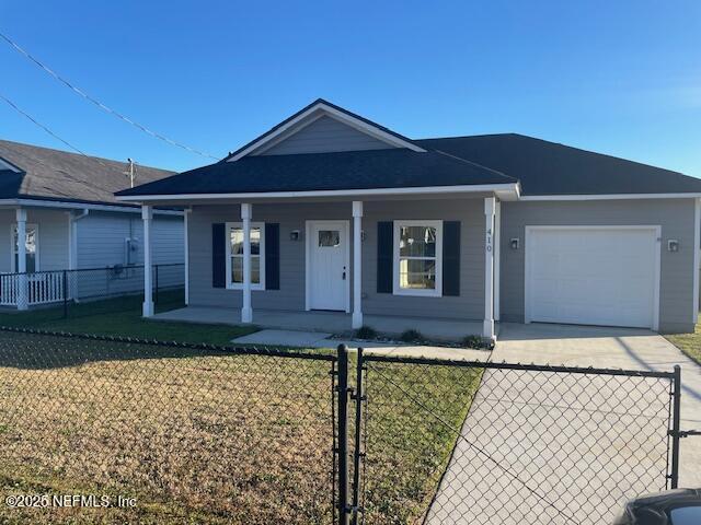 ranch-style house with a front lawn, covered porch, and a garage