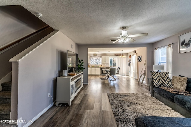 living room featuring ceiling fan, dark wood-type flooring, and a textured ceiling