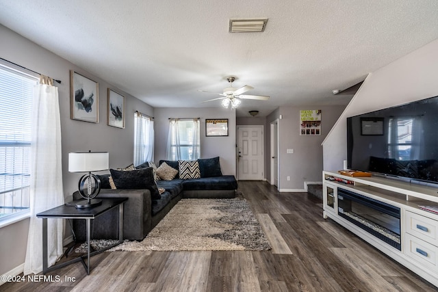 living room featuring a textured ceiling, dark hardwood / wood-style floors, a wealth of natural light, and ceiling fan