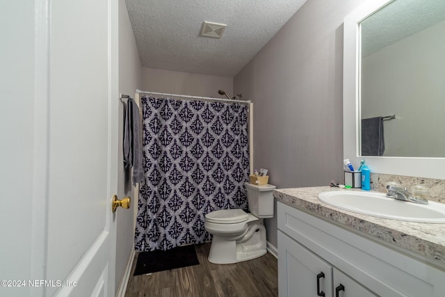 bathroom featuring a shower with curtain, wood-type flooring, a textured ceiling, toilet, and vanity