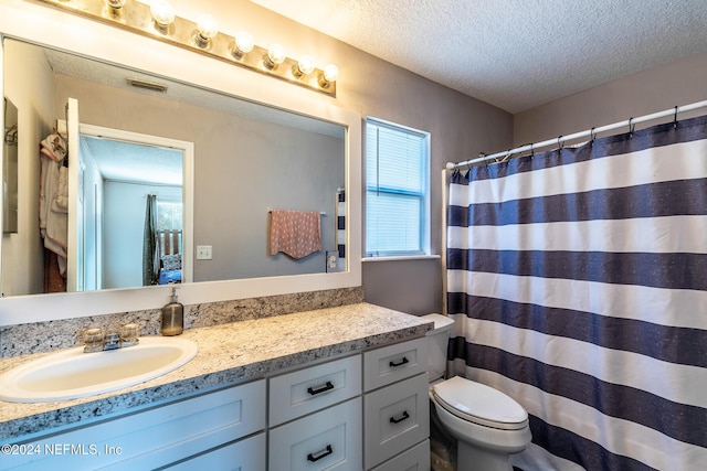 bathroom with walk in shower, vanity, a textured ceiling, and toilet