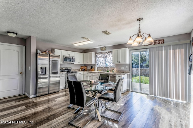 dining room with a chandelier, sink, wood-type flooring, and a textured ceiling