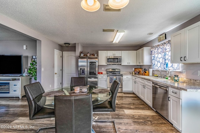 kitchen featuring sink, stainless steel appliances, dark hardwood / wood-style floors, a textured ceiling, and white cabinets