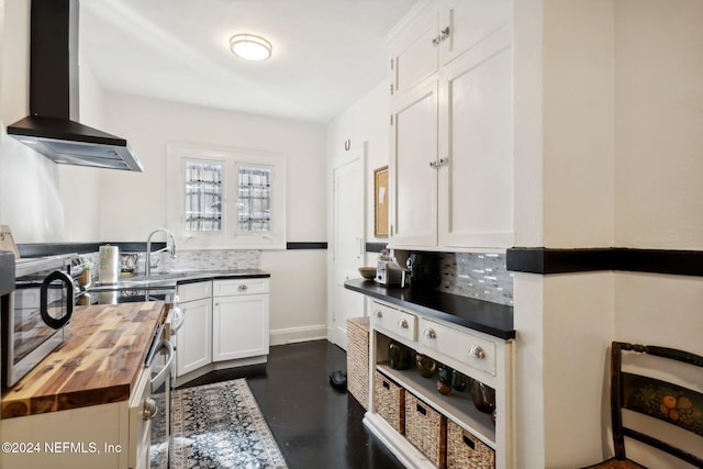 kitchen featuring tasteful backsplash, wall chimney exhaust hood, sink, white cabinets, and butcher block countertops