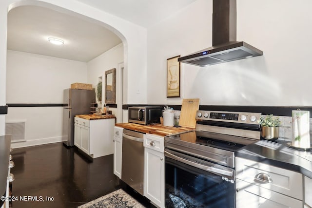 kitchen featuring stainless steel appliances, crown molding, exhaust hood, white cabinetry, and butcher block counters