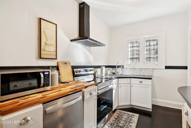 kitchen featuring white cabinetry, sink, stainless steel appliances, wall chimney range hood, and butcher block countertops