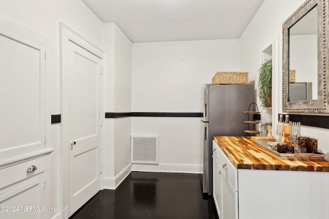 kitchen featuring stainless steel refrigerator, butcher block counters, white cabinetry, and ornamental molding