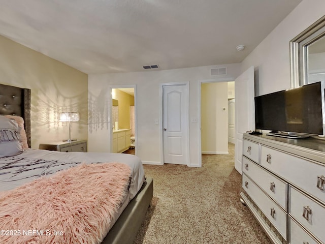 bedroom with ensuite bath and light carpet