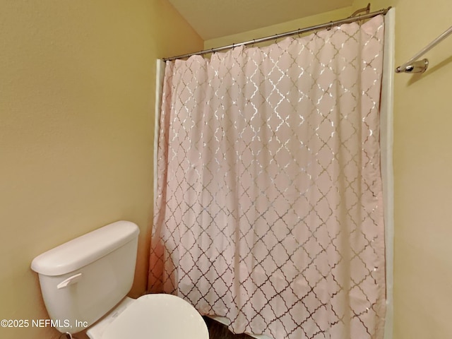 bathroom featuring toilet and curtained shower