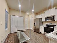 kitchen featuring white cabinets, hardwood / wood-style floors, stainless steel appliances, and hanging light fixtures