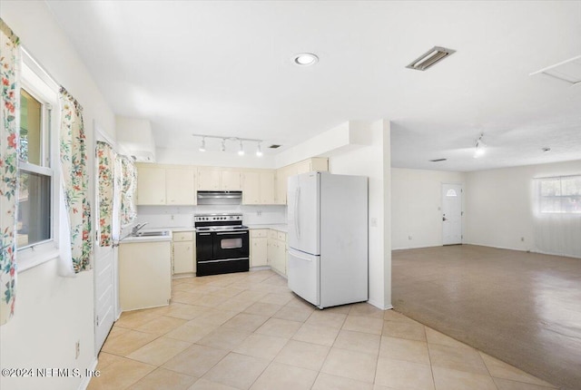 kitchen with light carpet, a healthy amount of sunlight, sink, white refrigerator, and black / electric stove