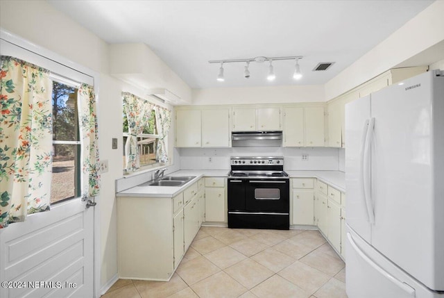 kitchen featuring white refrigerator, a wealth of natural light, range with electric cooktop, and sink