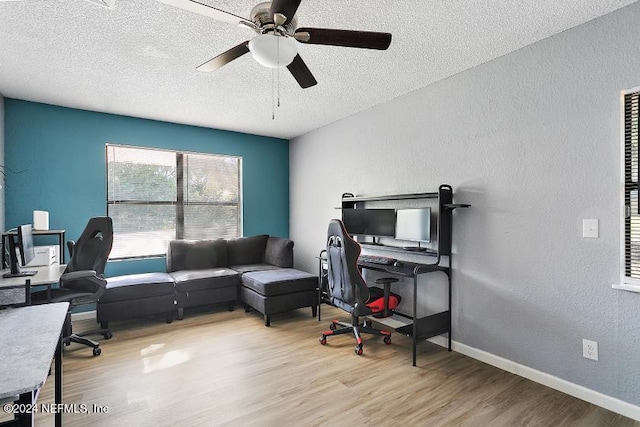 home office with ceiling fan, a textured ceiling, and light wood-type flooring