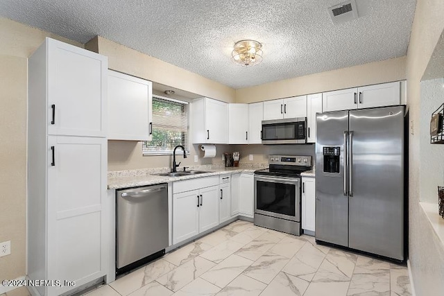 kitchen with sink, white cabinets, stainless steel appliances, and a textured ceiling