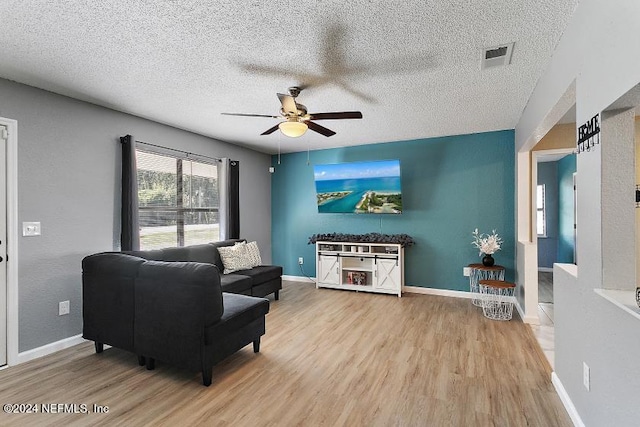 living room featuring hardwood / wood-style floors, ceiling fan, and a textured ceiling