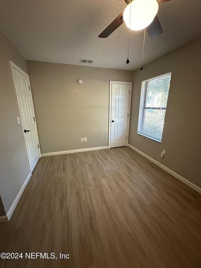 unfurnished room with hardwood / wood-style floors, ceiling fan, and a textured ceiling