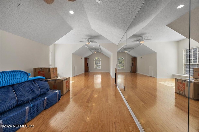 additional living space with lofted ceiling, light hardwood / wood-style floors, and a textured ceiling