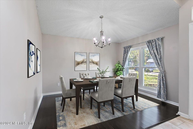 dining area with a textured ceiling, hardwood / wood-style flooring, and an inviting chandelier