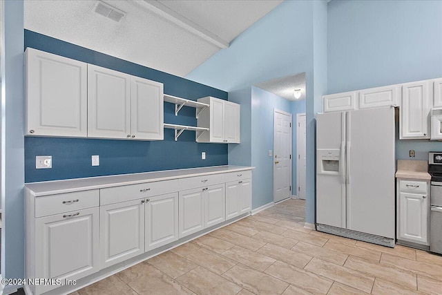 kitchen featuring white cabinets, a textured ceiling, white appliances, and lofted ceiling with beams