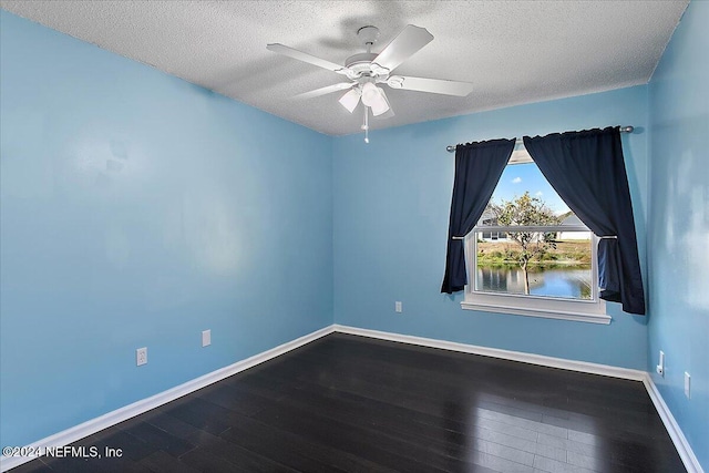 unfurnished room featuring a textured ceiling, ceiling fan, a water view, and dark hardwood / wood-style floors