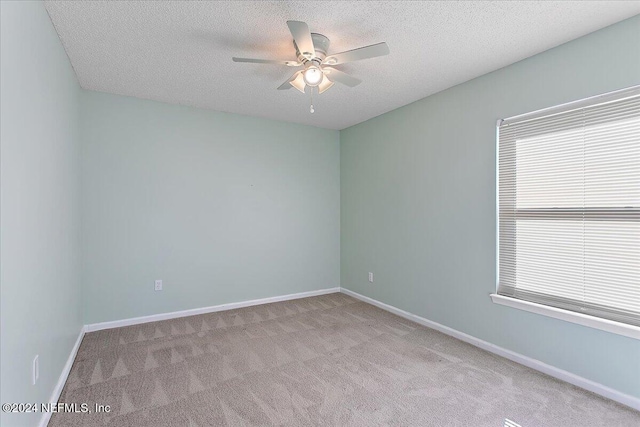 spare room featuring light carpet, ceiling fan, and a textured ceiling