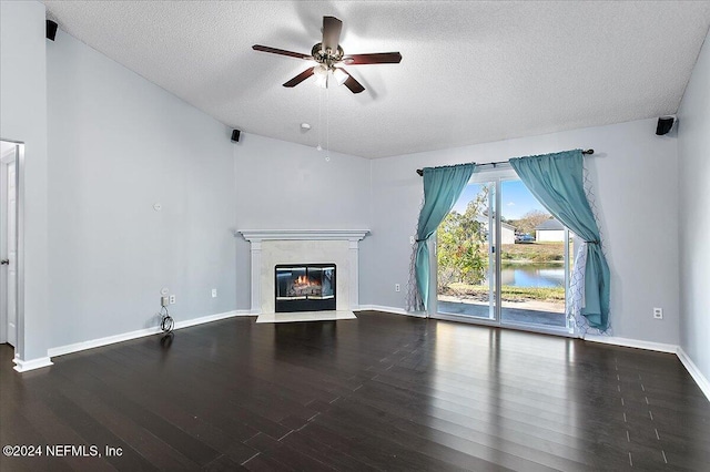 unfurnished living room with ceiling fan, a water view, a textured ceiling, and hardwood / wood-style flooring