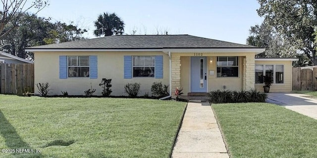 view of front of home with a shingled roof, fence, a front lawn, and stucco siding