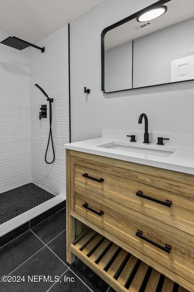 bathroom with tile patterned floors, vanity, and tiled shower