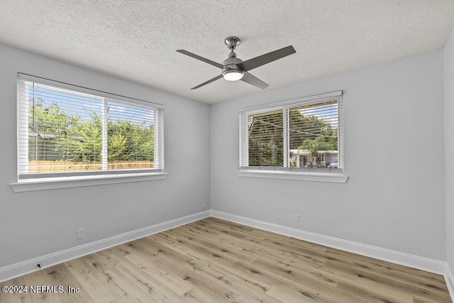 empty room with ceiling fan, light hardwood / wood-style flooring, and a textured ceiling