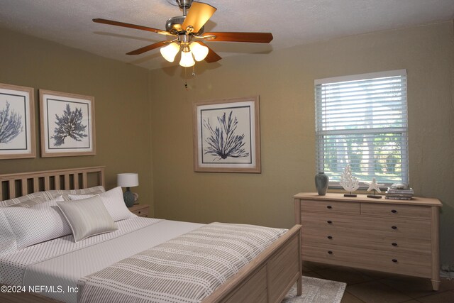 tiled bedroom featuring ceiling fan and a textured ceiling