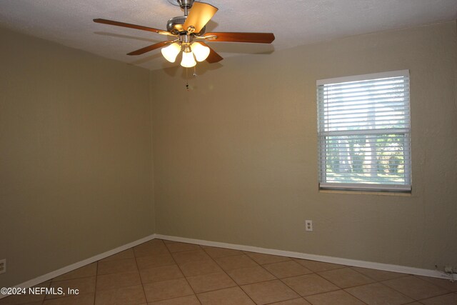 empty room featuring ceiling fan, tile patterned flooring, and a textured ceiling