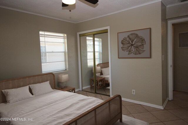 bedroom with ceiling fan, a closet, light tile patterned flooring, and ornamental molding