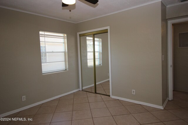 unfurnished bedroom with ceiling fan, a closet, and crown molding