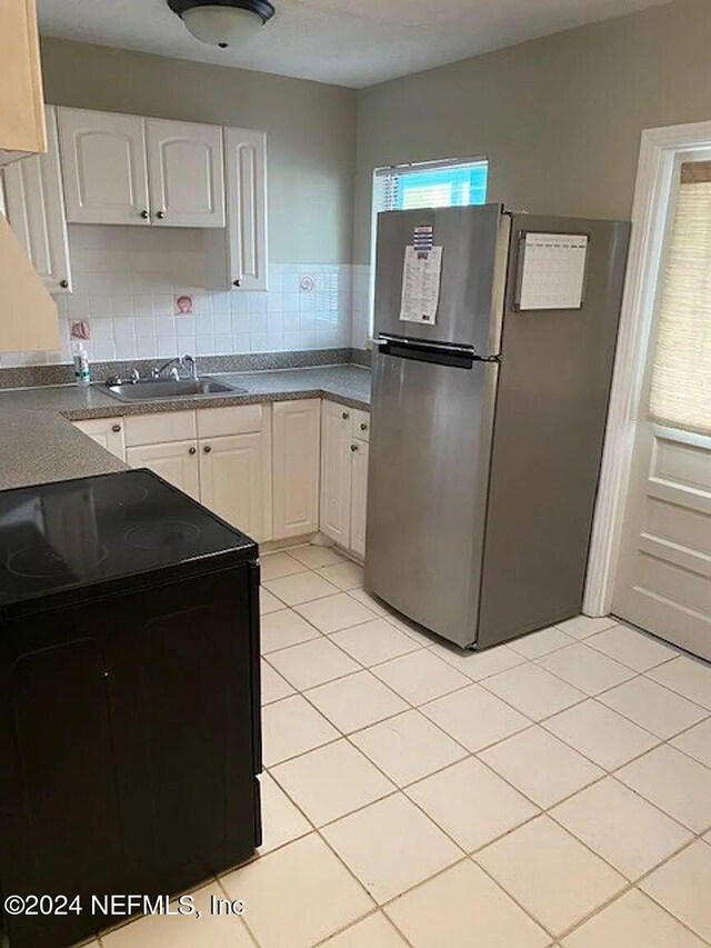 kitchen featuring black range with electric cooktop, white cabinetry, sink, and stainless steel refrigerator