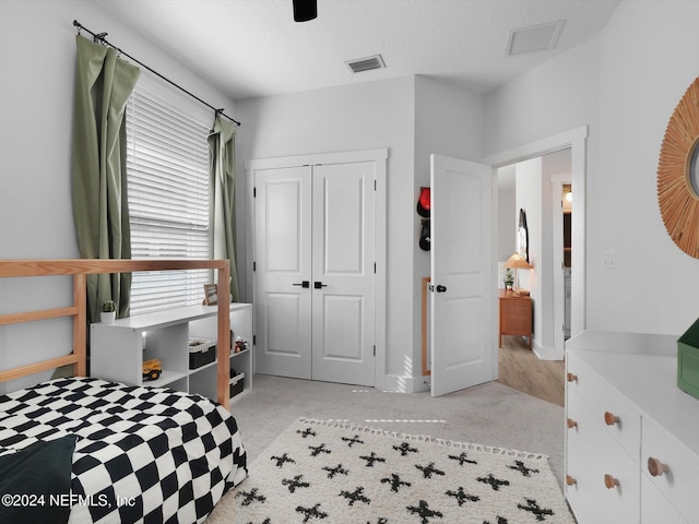 bedroom featuring light carpet, a textured ceiling, and a closet