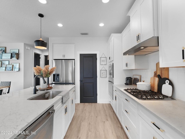 kitchen with light stone countertops, sink, hanging light fixtures, white cabinets, and appliances with stainless steel finishes