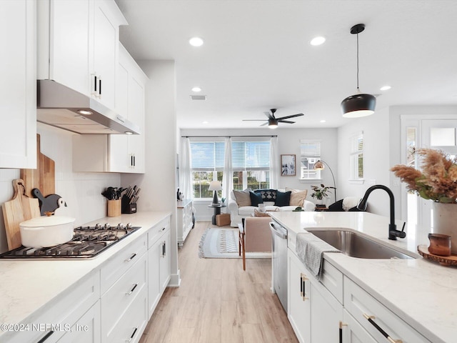 kitchen featuring white cabinetry, sink, stainless steel appliances, light hardwood / wood-style flooring, and decorative light fixtures