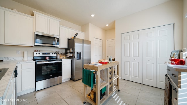 kitchen featuring white cabinets, appliances with stainless steel finishes, and light tile patterned floors