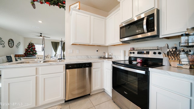 kitchen with sink, stainless steel appliances, light tile patterned floors, kitchen peninsula, and white cabinets