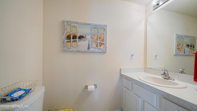 bathroom with vanity, toilet, and a textured ceiling