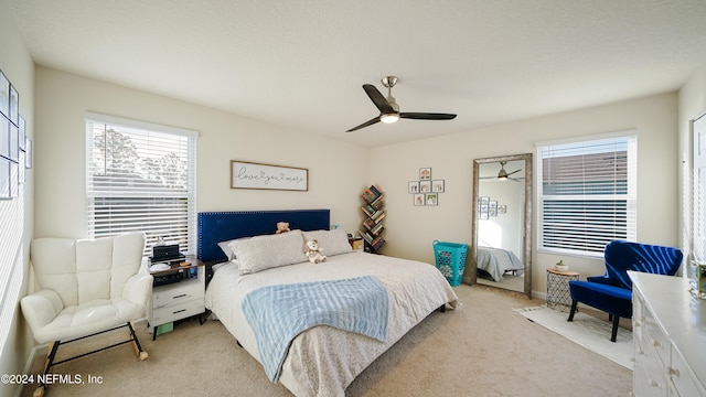 bedroom featuring a textured ceiling, ceiling fan, and light carpet