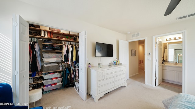 bedroom with ensuite bathroom, ceiling fan, light colored carpet, and sink