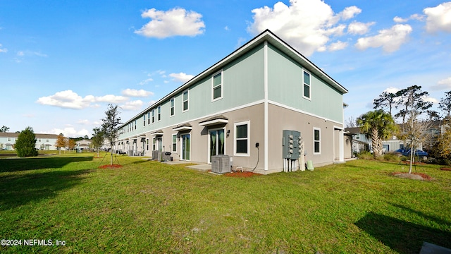 rear view of property featuring central AC and a yard