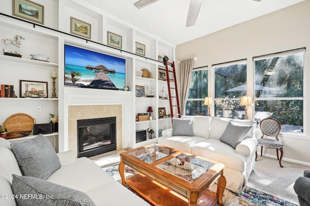 carpeted living room featuring built in features, ceiling fan, and a tiled fireplace