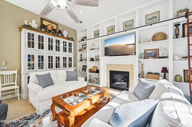 living room featuring built in shelves, ceiling fan, a fireplace, and carpet