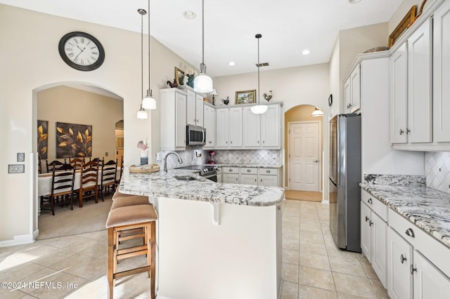 kitchen with tasteful backsplash, pendant lighting, a kitchen bar, and stainless steel appliances