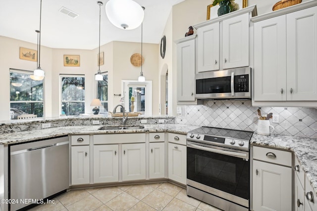 kitchen with sink, appliances with stainless steel finishes, decorative light fixtures, light tile patterned flooring, and white cabinetry