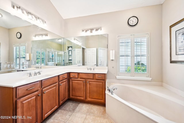 bathroom with tile patterned flooring, vanity, a tub to relax in, and plenty of natural light