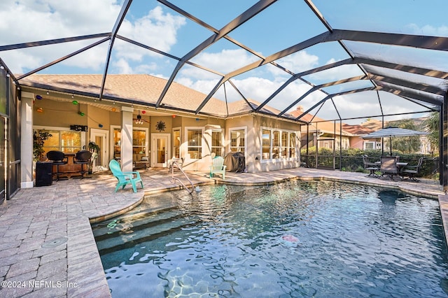 view of swimming pool with glass enclosure, ceiling fan, and a patio