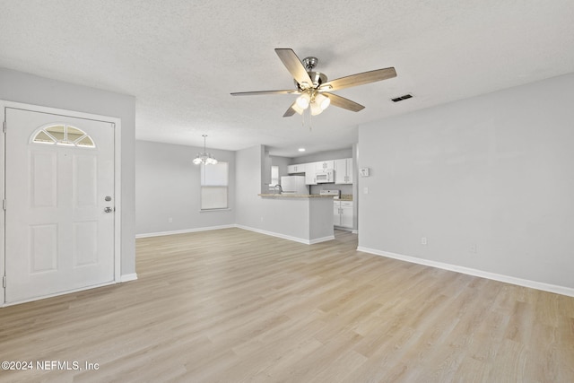 unfurnished living room with a healthy amount of sunlight, a textured ceiling, and light hardwood / wood-style flooring